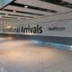 Letreiro International Arrivals no corredor de chegadas do aeroporto de Heathrow.